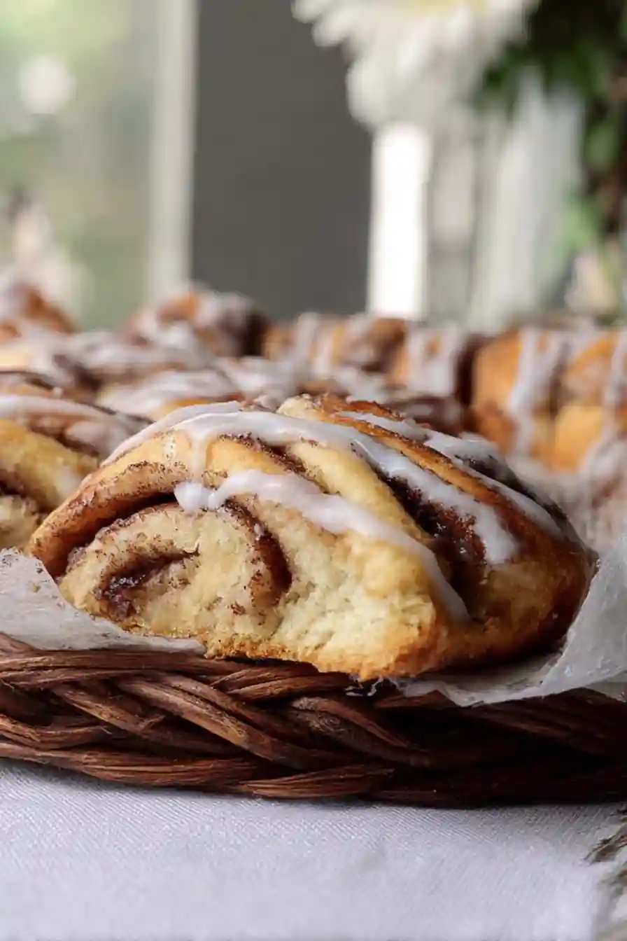 Close-up of cinnamon roll scone with icing in a wicker basket Basket of Glazed Cinnamon Roll Scones